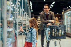 A little girl is showing her dad ice cream in the supermarket fridge