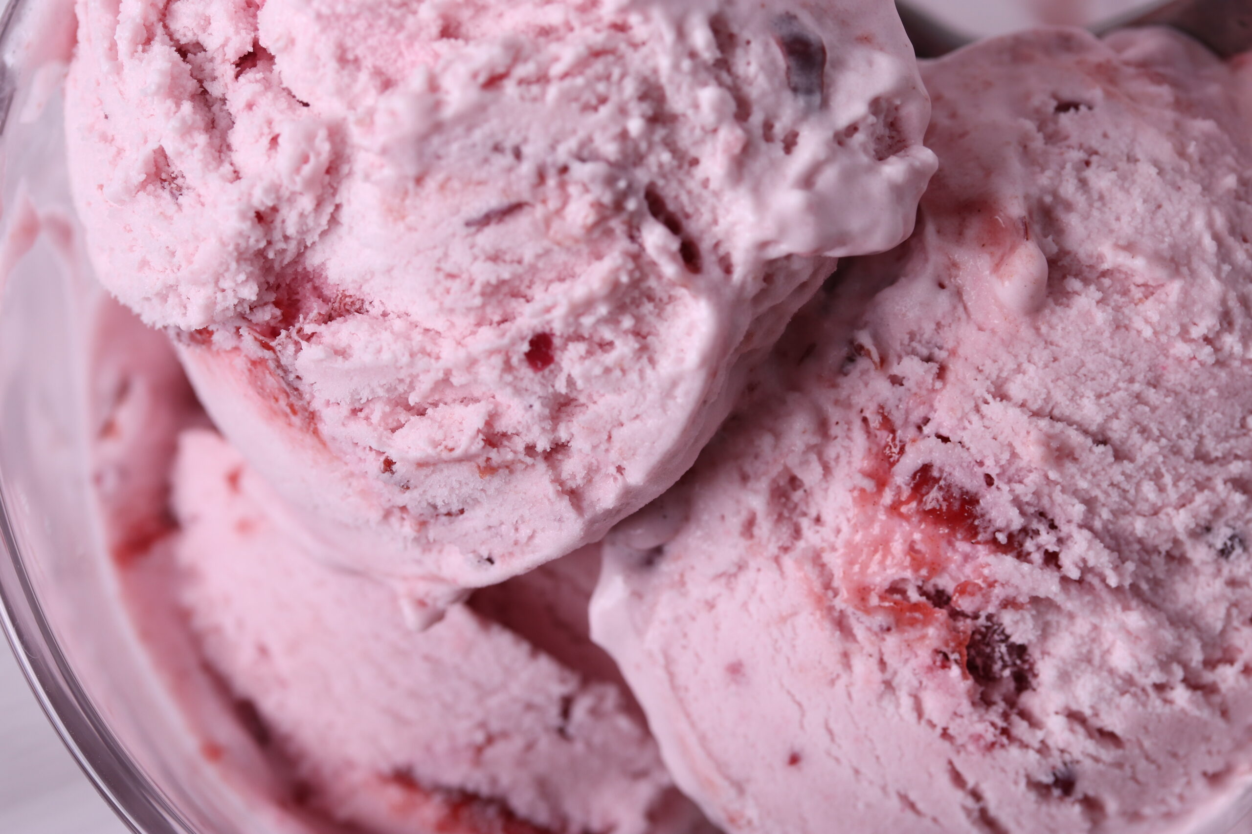 tasty cold melting strawberry and raspberry icecream in a glass container. close up shot.
