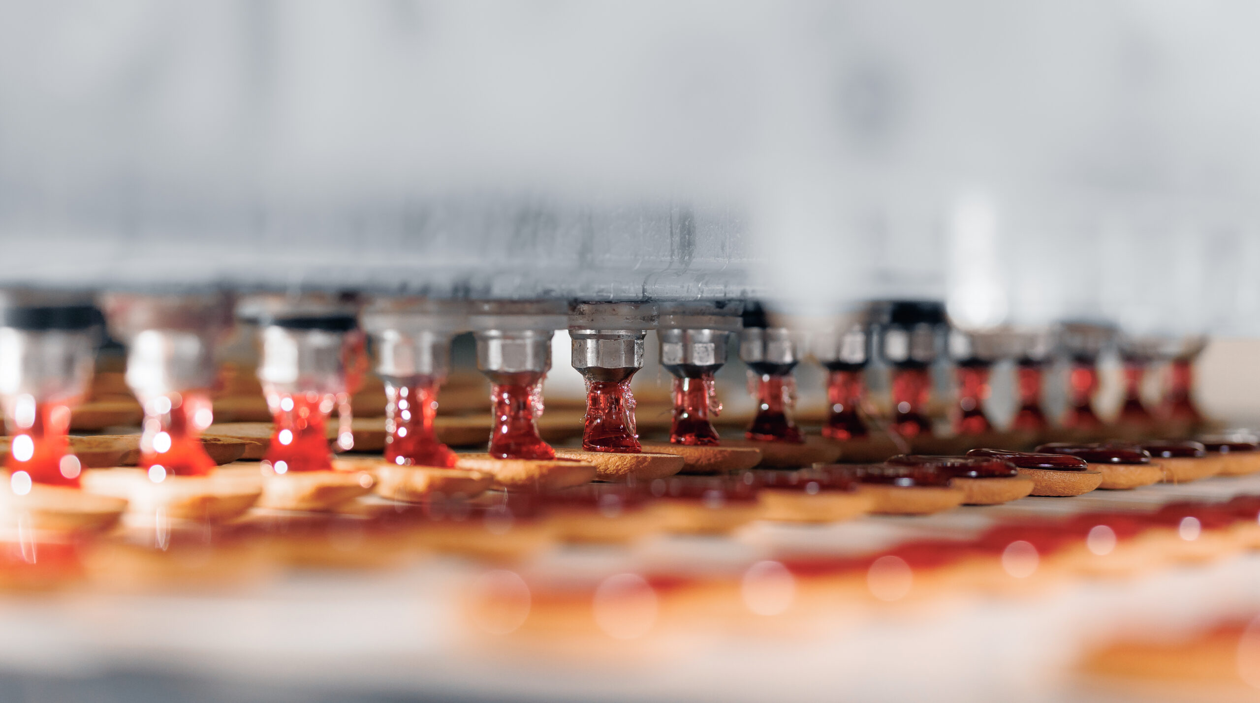 Food industry banner, Red fruit jam squeezed onto cookies biscuit production in modern factory on conveyor belt.