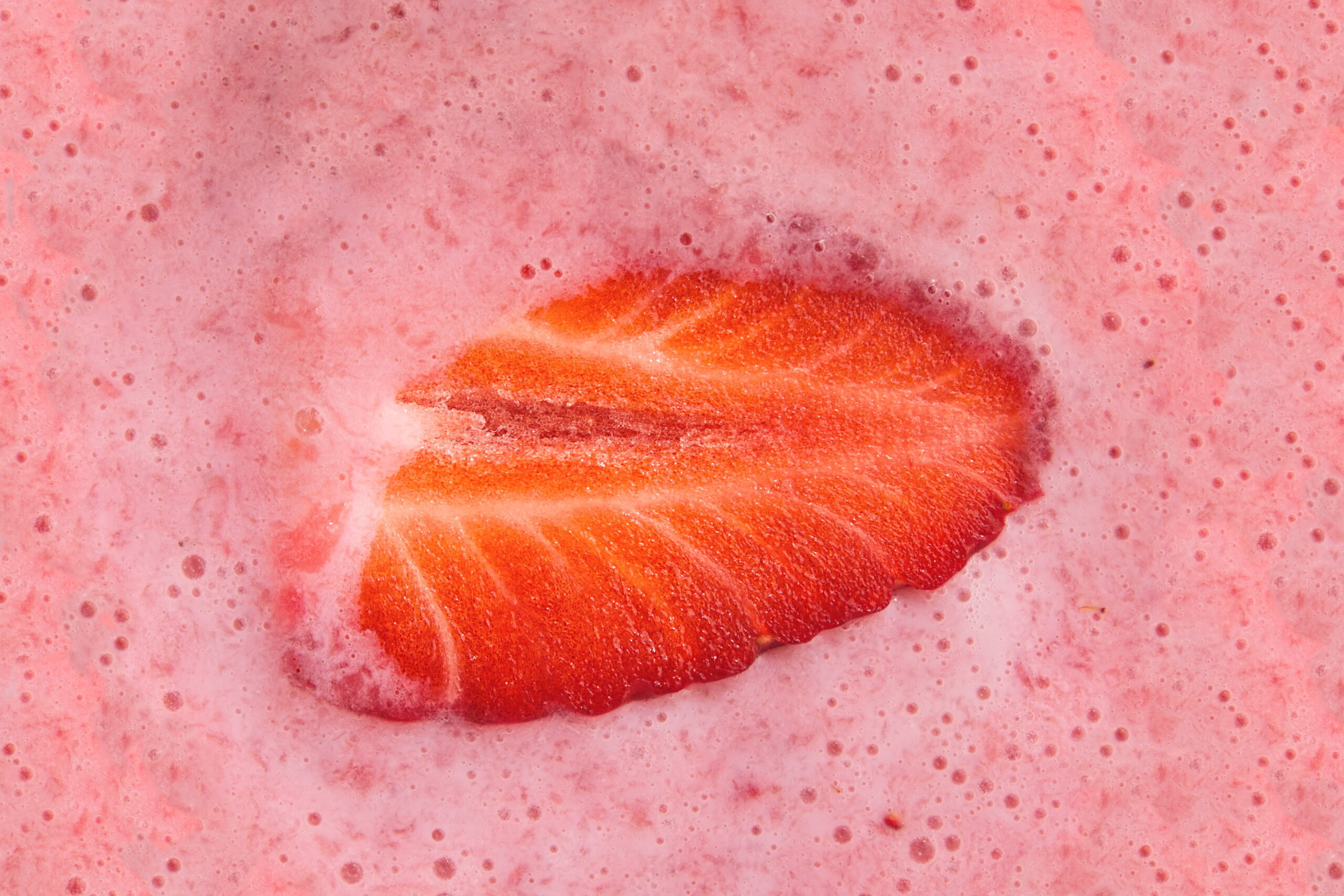 Close-up of strawberry in pink fruit base, representing clean-label shelf-stable formulation.

Halved Strawberry in Milk Shake Closeup Top View