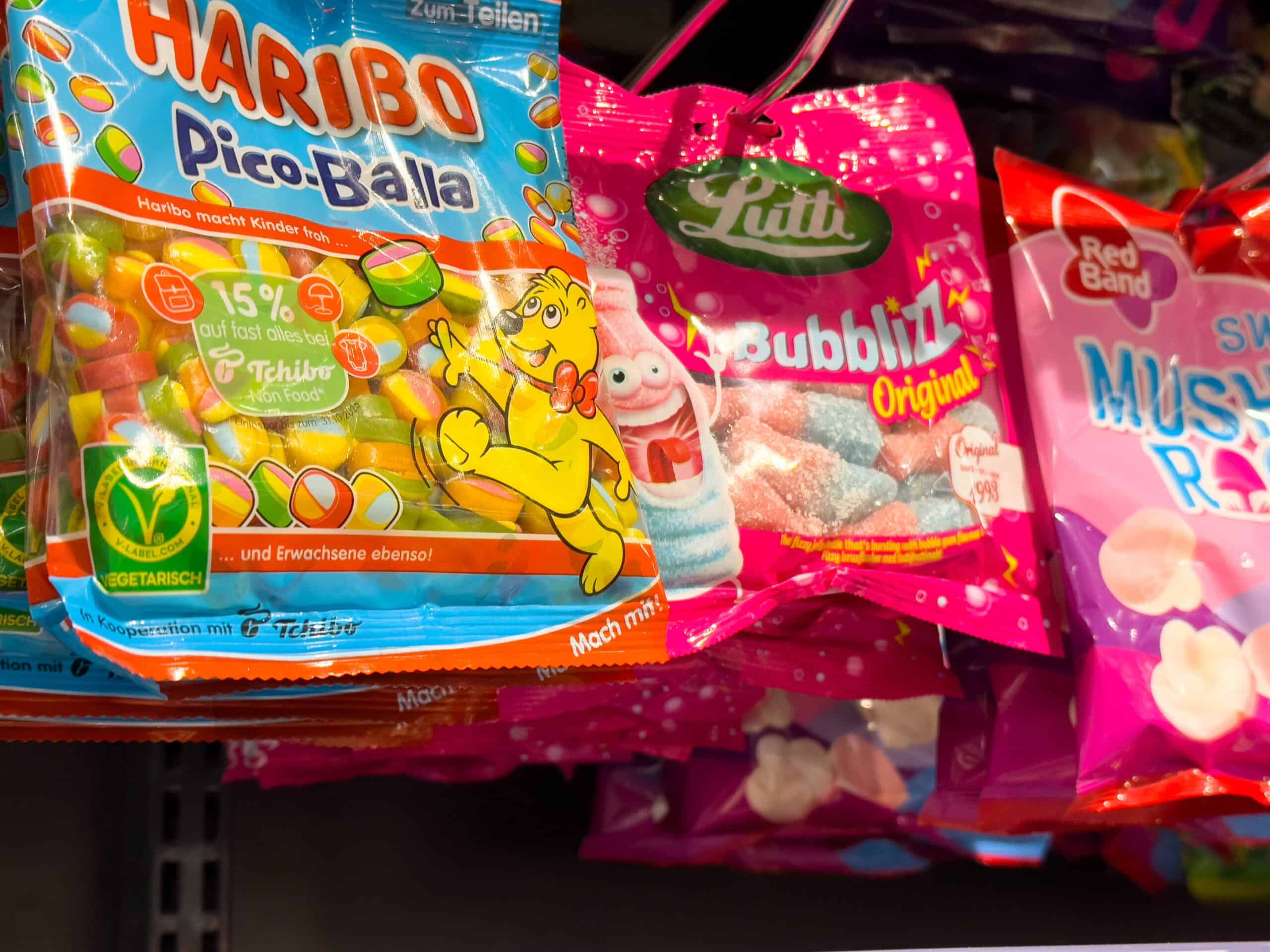 Colorful bags of Haribo Pico-Balla and Lutti Bubblizz gummy candies displayed on a store shelf