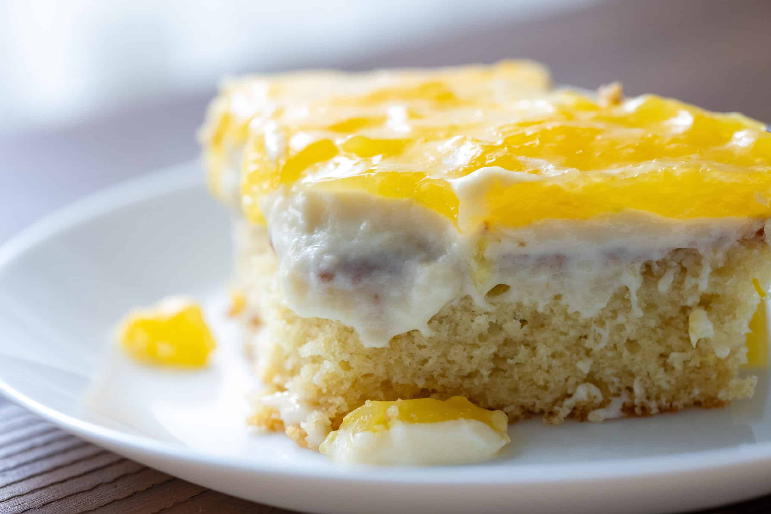 Slice of golden citrus cake with lemon frosting on a white plate, representing the international elevation of classic citrus bakery flavors