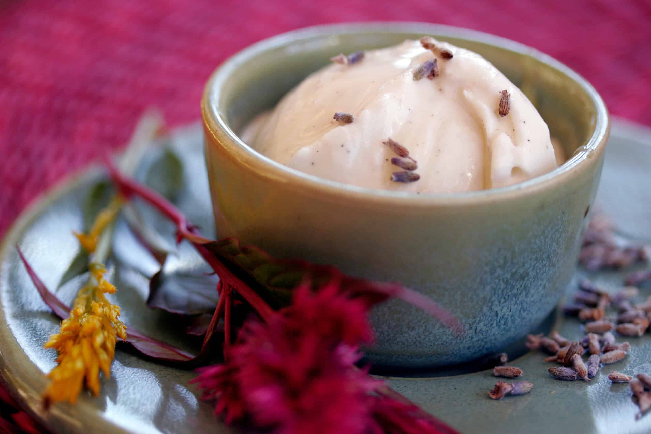 Creamy ice cream in ceramic bowl drizzled with golden honey and topped with fresh purple lavender flowers