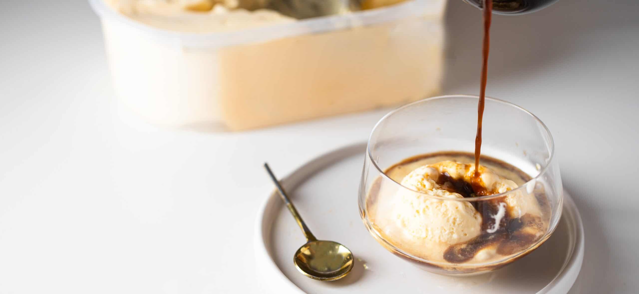Espresso poured over a vanilla ice cream scoop in a glass cup with a gold spoon — pairing strong flavors to mask protein off-notes in ice cream formulation.