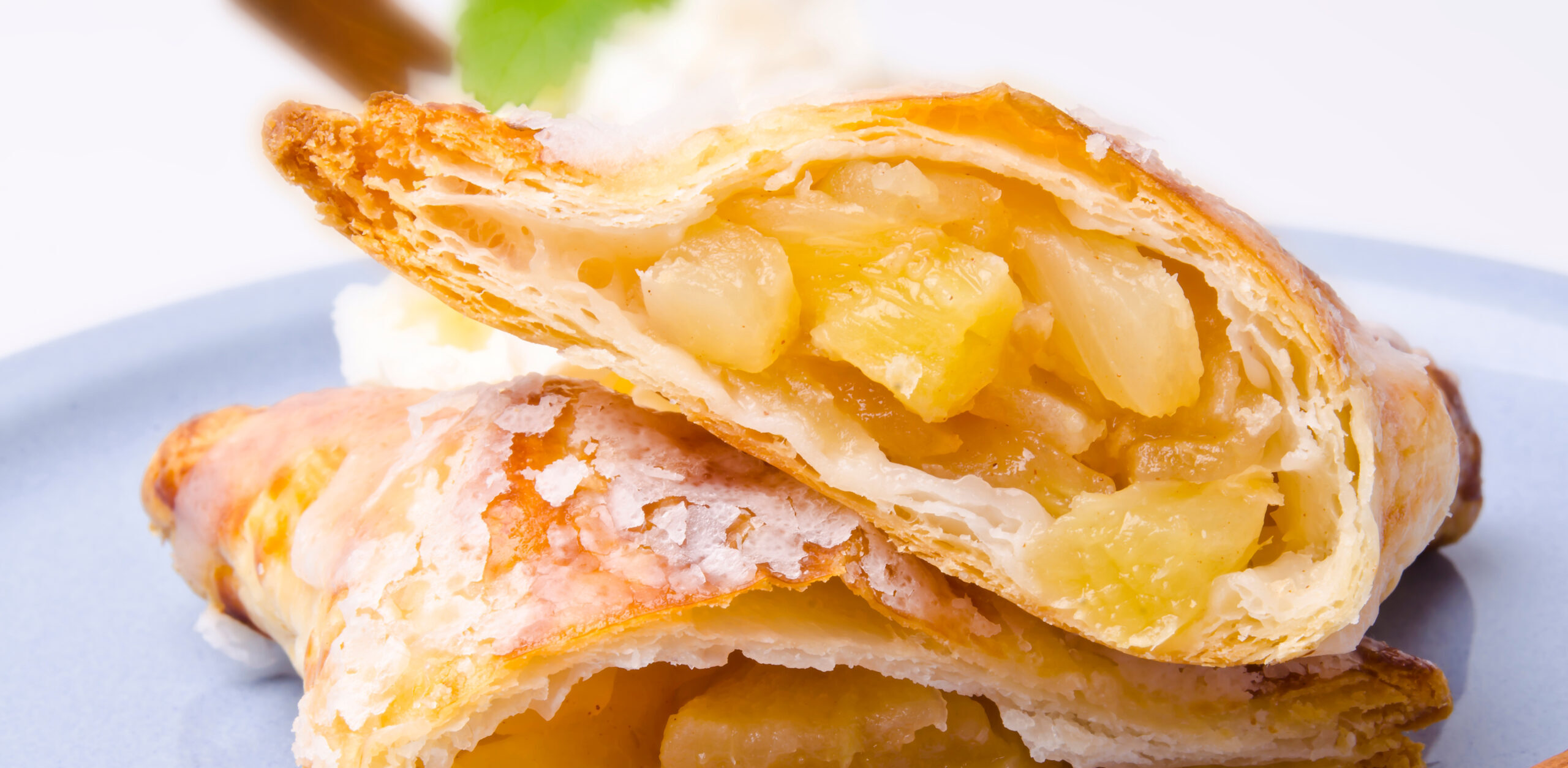 Apple turnover cut open on a plate showing chunky apple bake-stable fruit filling staying neatly contained within the puff pastry.