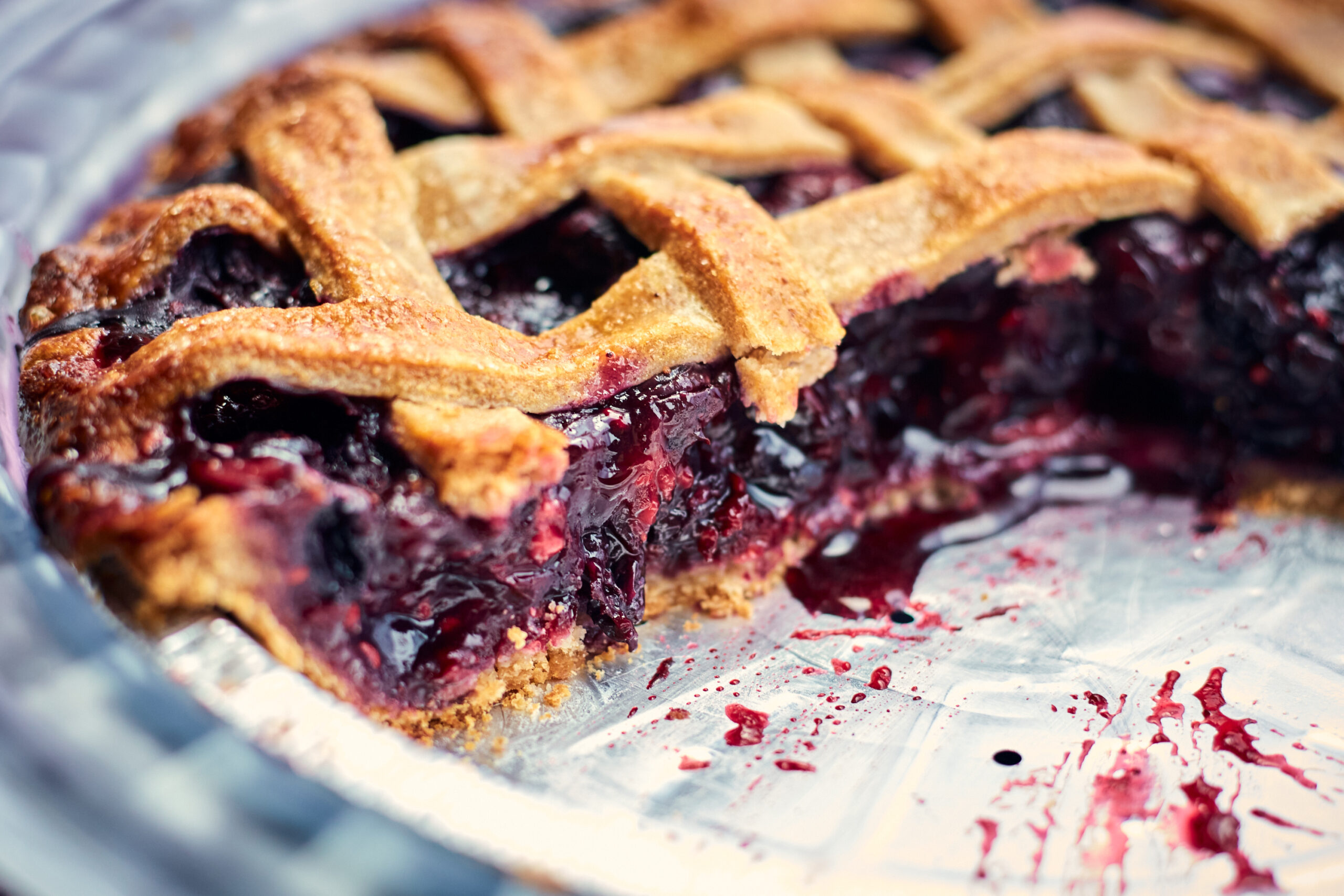 Close-up of a freshly baked cherry pie with lattice crust and filling spilling out.