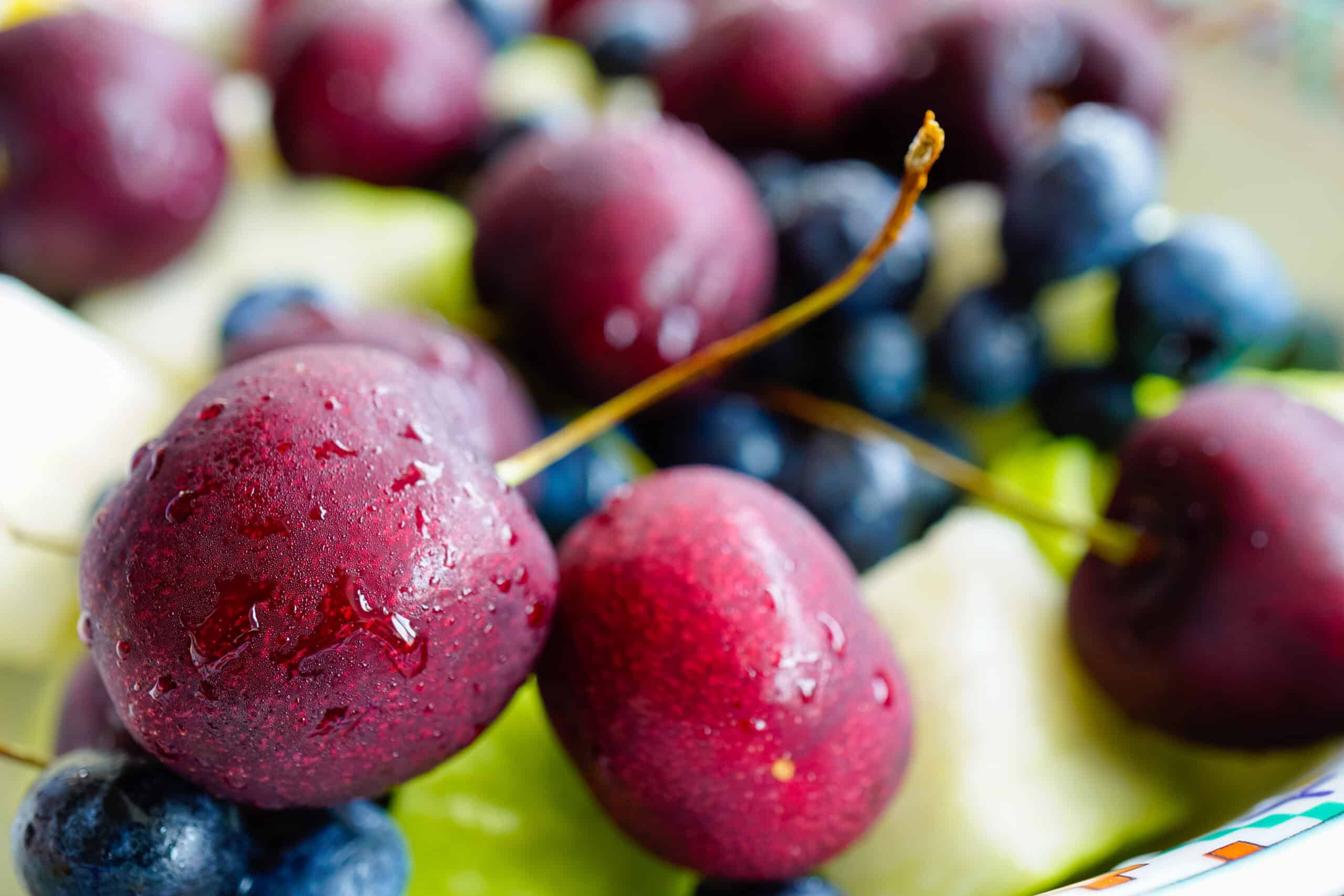 Macro of fresh wet cherries and blueberries, representing the premium fruit behind high-quality bake-stable fruit fillings.