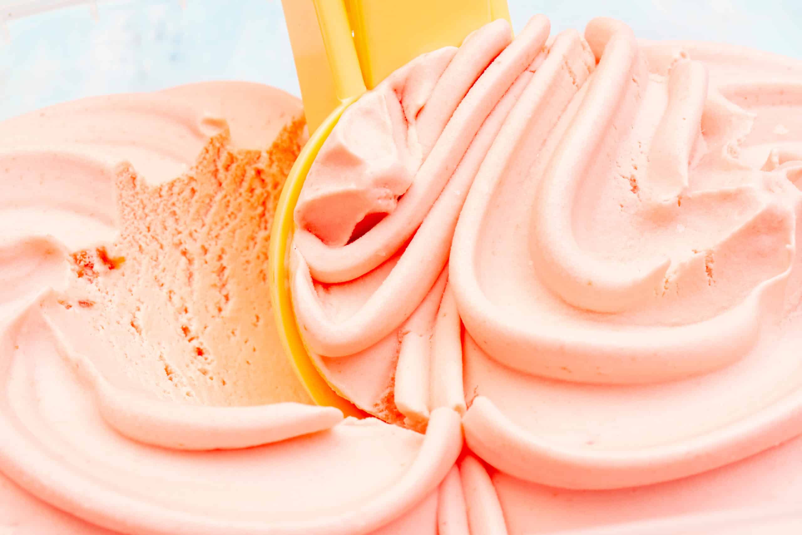 Scoop pulling through soft, creamy peach-colored ice cream, the smooth texture natural stabilizers protect, an ingredient transparency story worth telling on the label