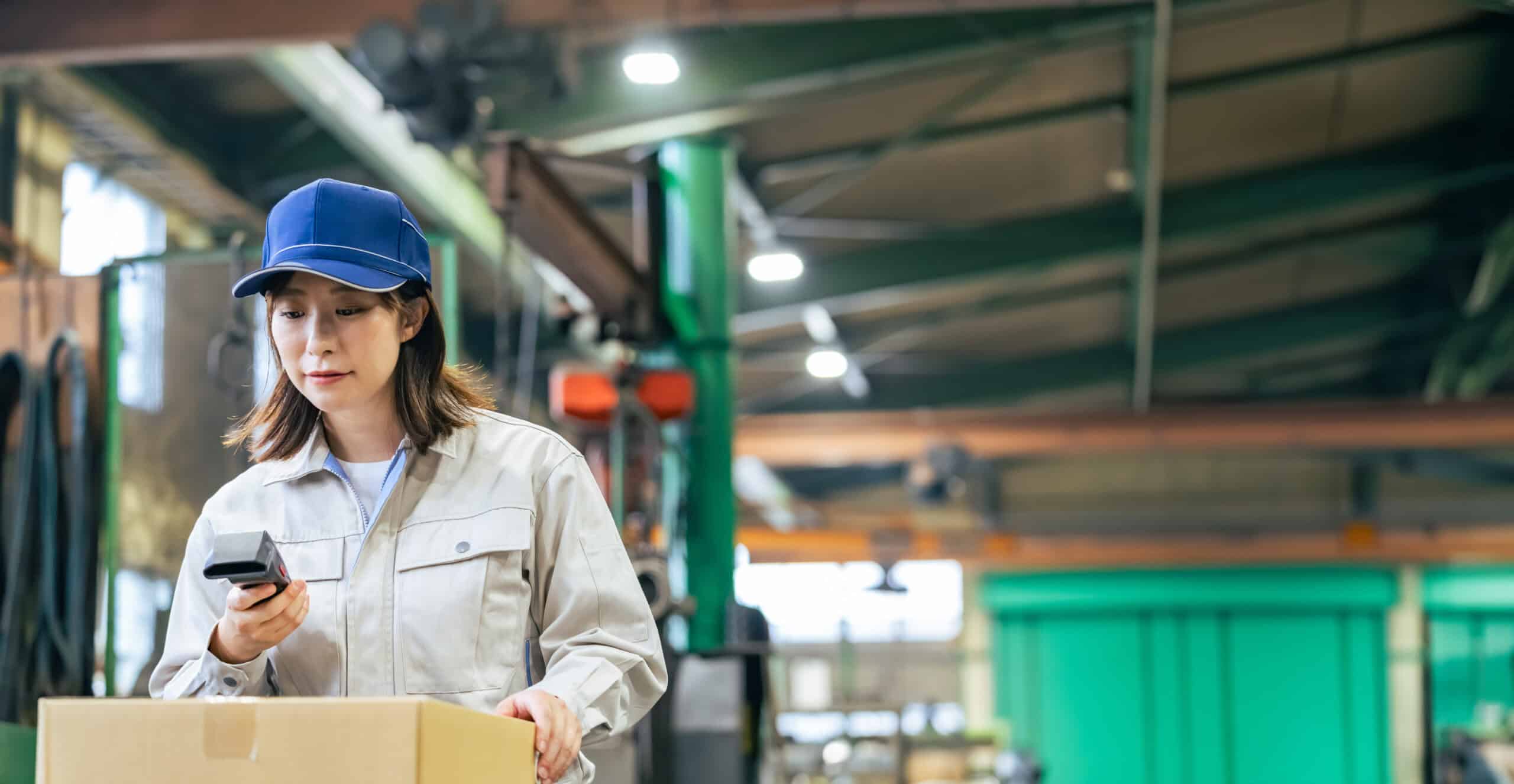 Worker scanning a barcode on a box in a warehouse, representing incoming ingredient inspection and certificate-of-analysis traceability verification.