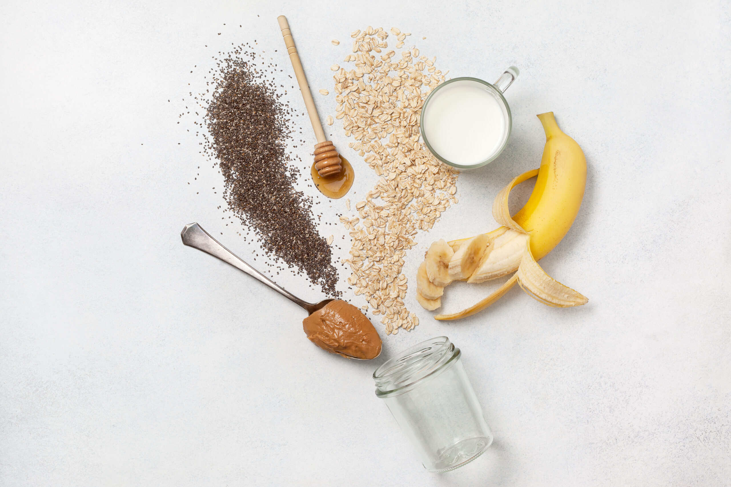 Overhead flat lay of simple recognizable ingredients including oats, banana, milk, honey, chia, and nut butter, the foundation of clean label consumer acceptance