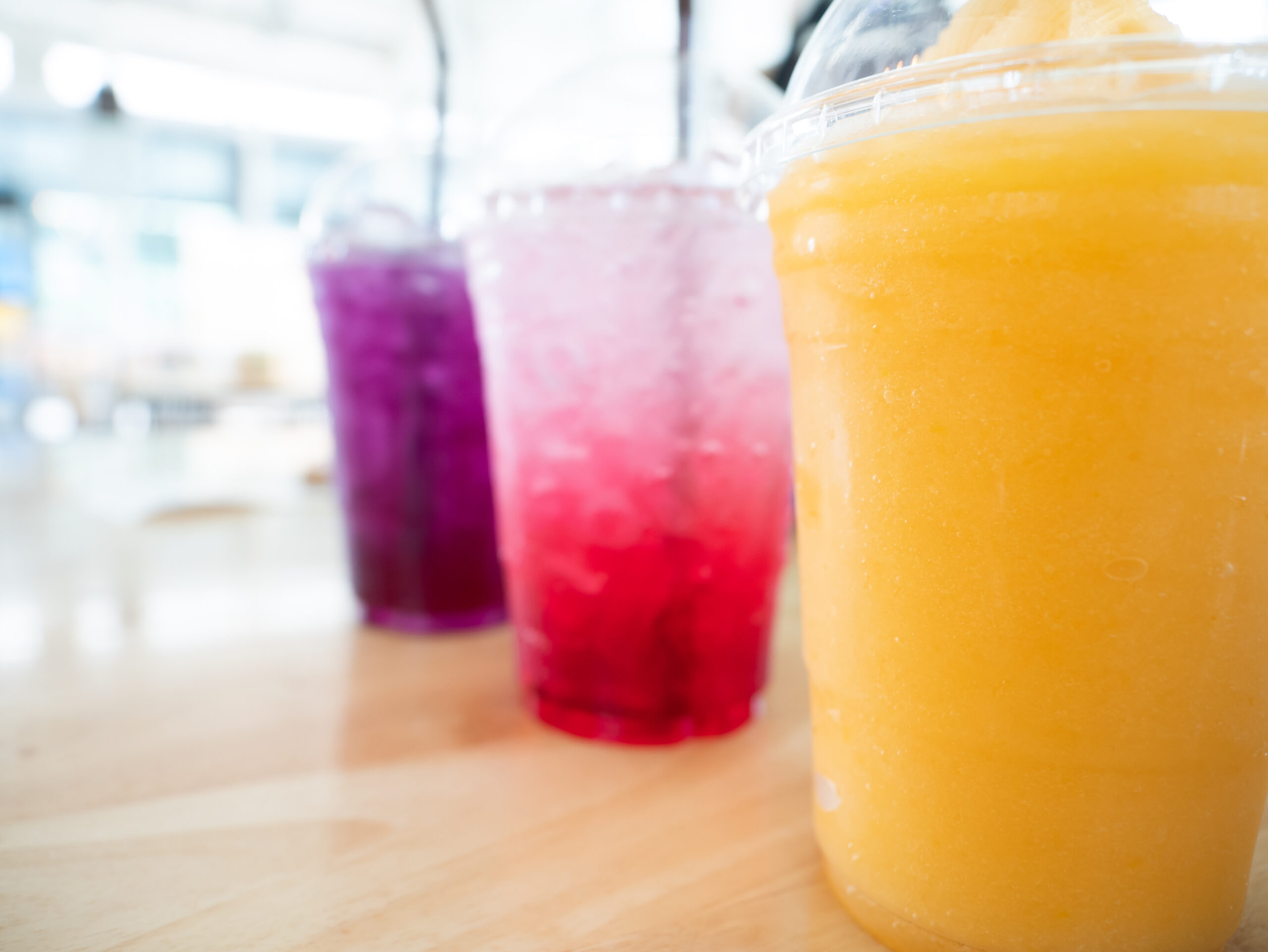 Three brightly colored iced drinks on a counter showing beverage menu variety in food service
