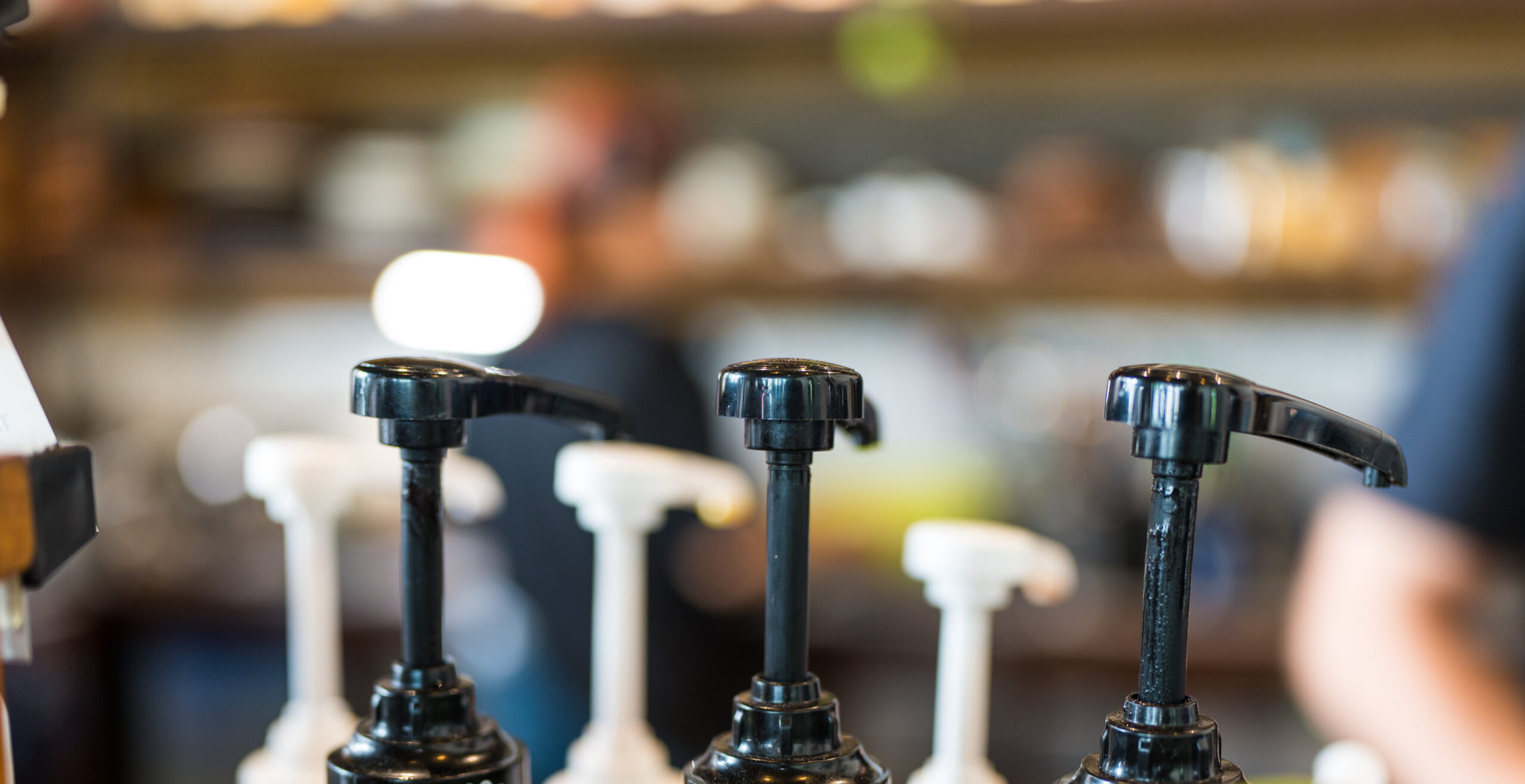 Flavor syrup pumps at a coffee bar station used to build trending beverage menu items